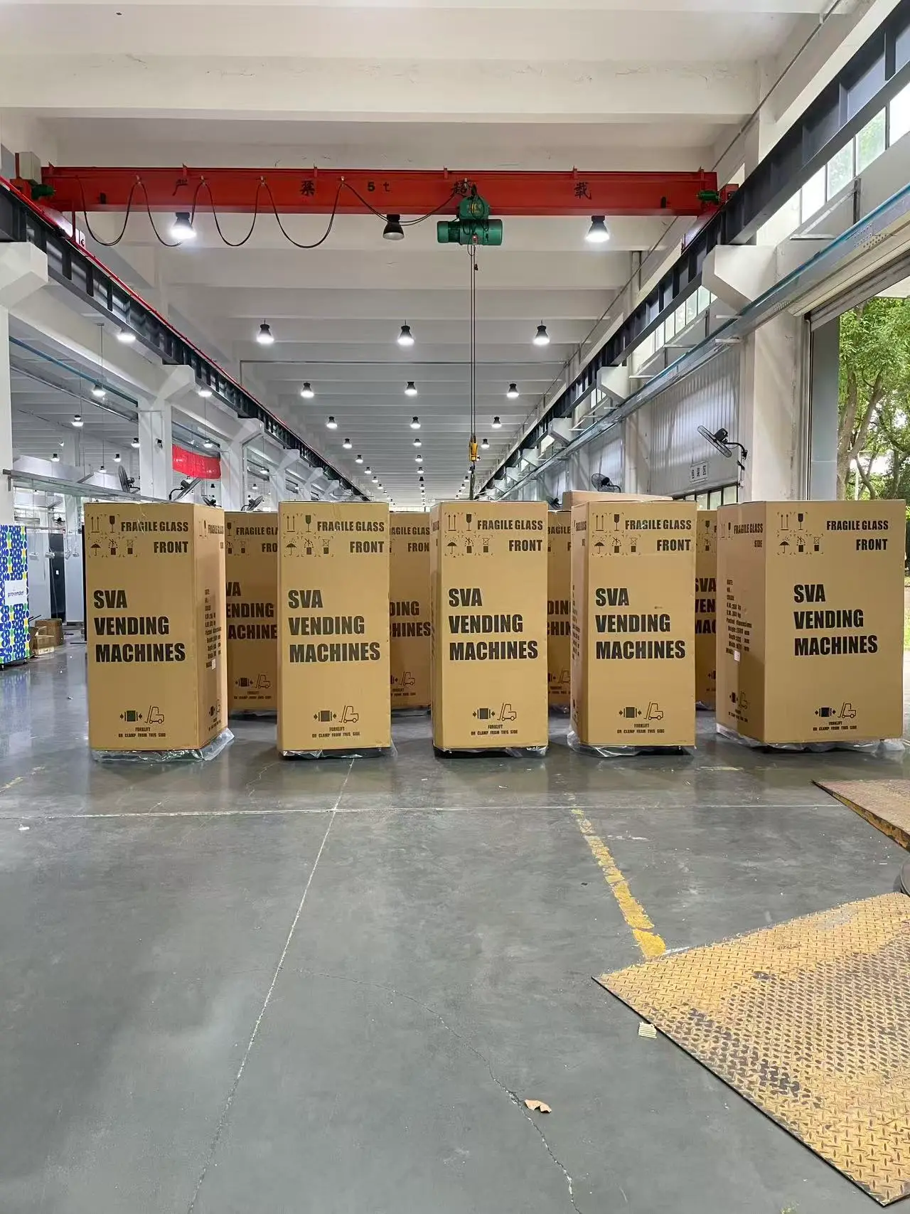 Finished vending machines in cartons lined up in factory warehouse, ready for container loading